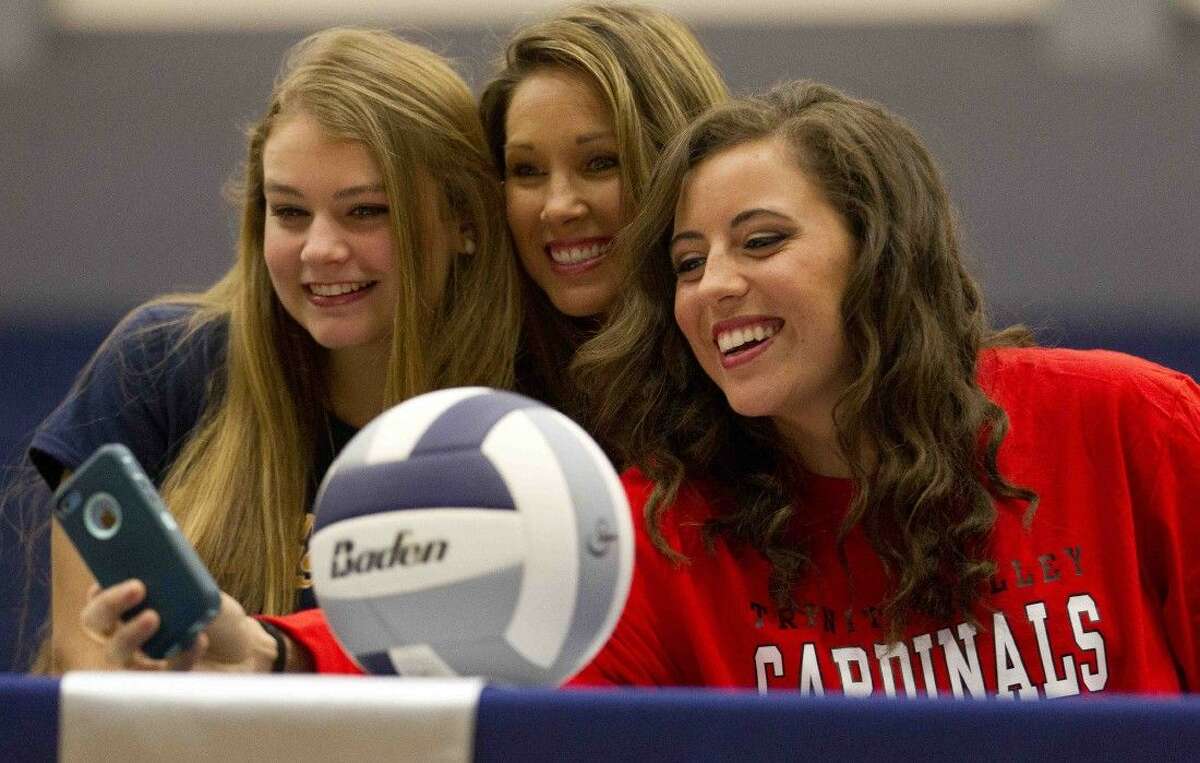Volleyball players Savannah Rutledge, left, and Alicia Bauersfeld take a selfie with coach Candice Collins during a college signing cermeony at College Park High School Wednesday. Rutledge signed to play volleyball for Texas A&M Commerce, while Bauersfeld will play for Trinity Valley Community College.