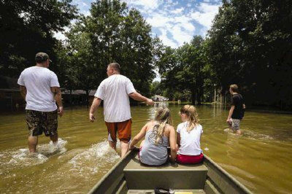River Plantation neighbors walk through receded flood waters to check on their homes on Sunday.