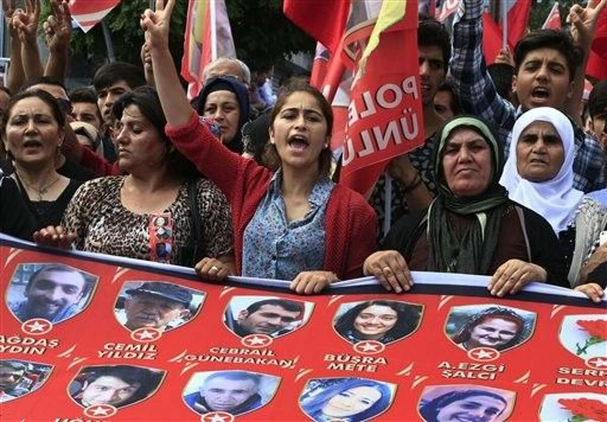 Mourners chant slogans as they carry a banner with pictures of victims of an explosion Monday in Suruc, southeastern Turkey, during a protest in Istanbul, Wednesday.