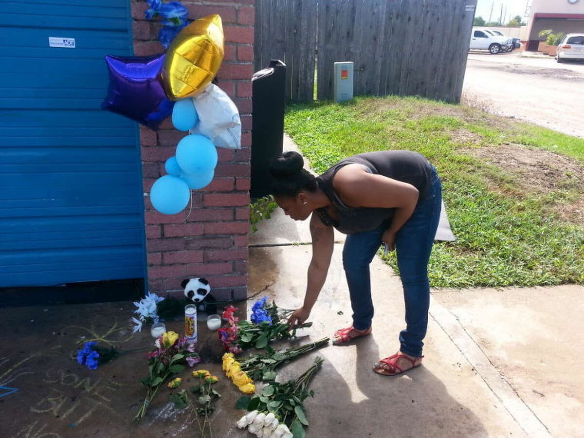 Donisha Francisco lays flowers in memory of her cousin, Donntay Borom, at the site of the triple-murder at Royal Wash Mobile Detailing & Car Wash Service, located at Avenue E near Murphy Road in Stafford.