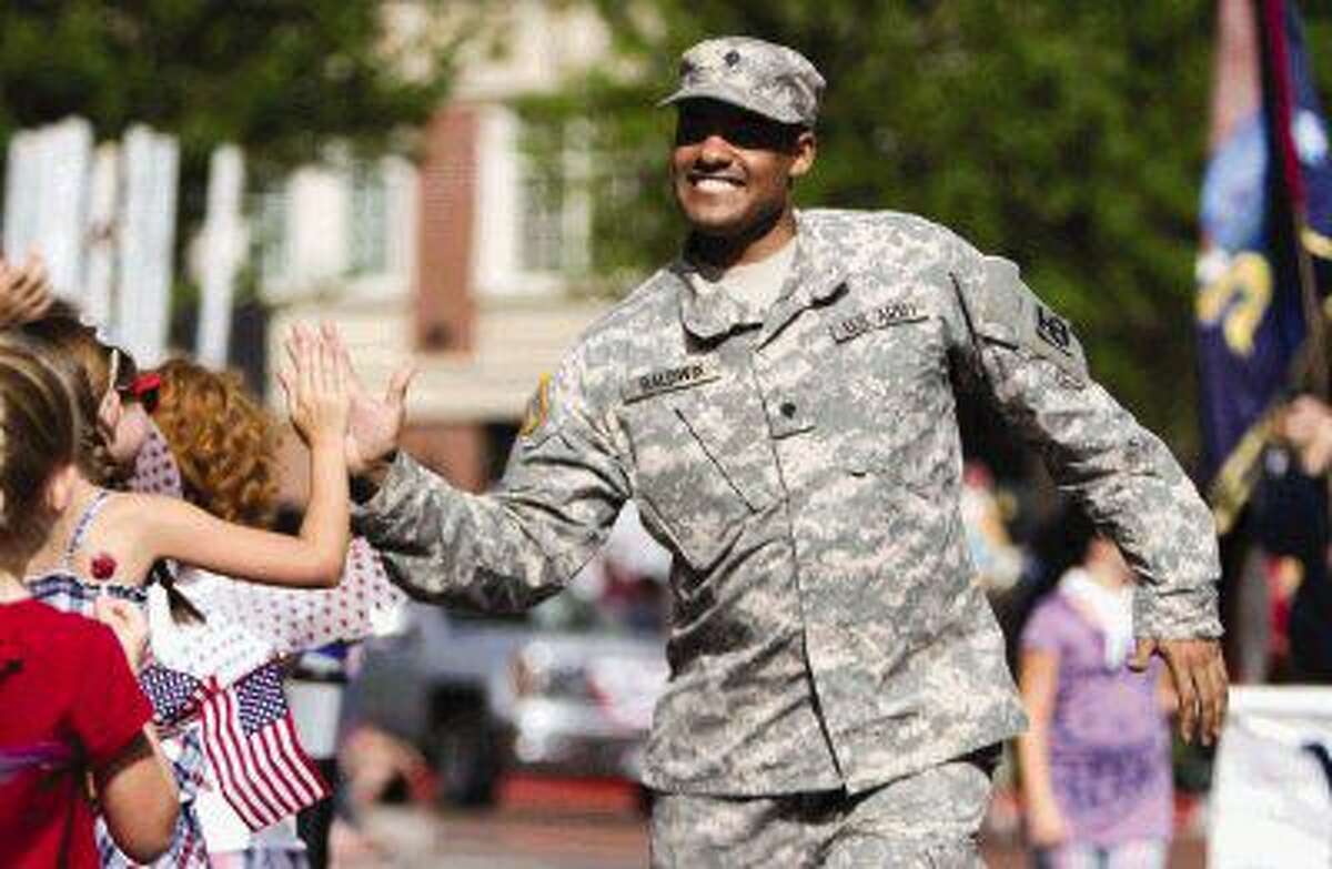 A soldier in the United States Army gives the crowd high-fives during the South County Fourth of July Parade on July 4, 2015 at Market Street.