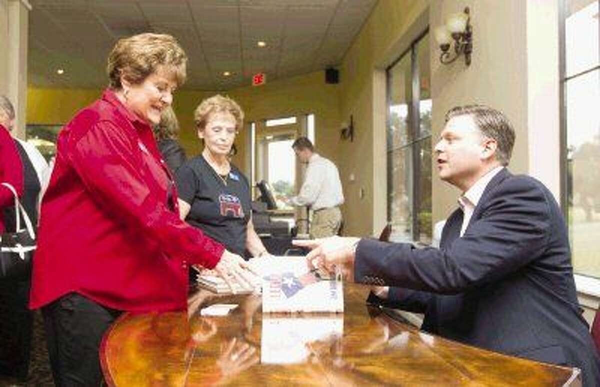 Nan McShan, left, gets a copy of “Allegiance” signed by KTRK Channel 13 news anchor and author Tom Abrahams after the Lake Conroe Area Republican Women meeting Thursday.