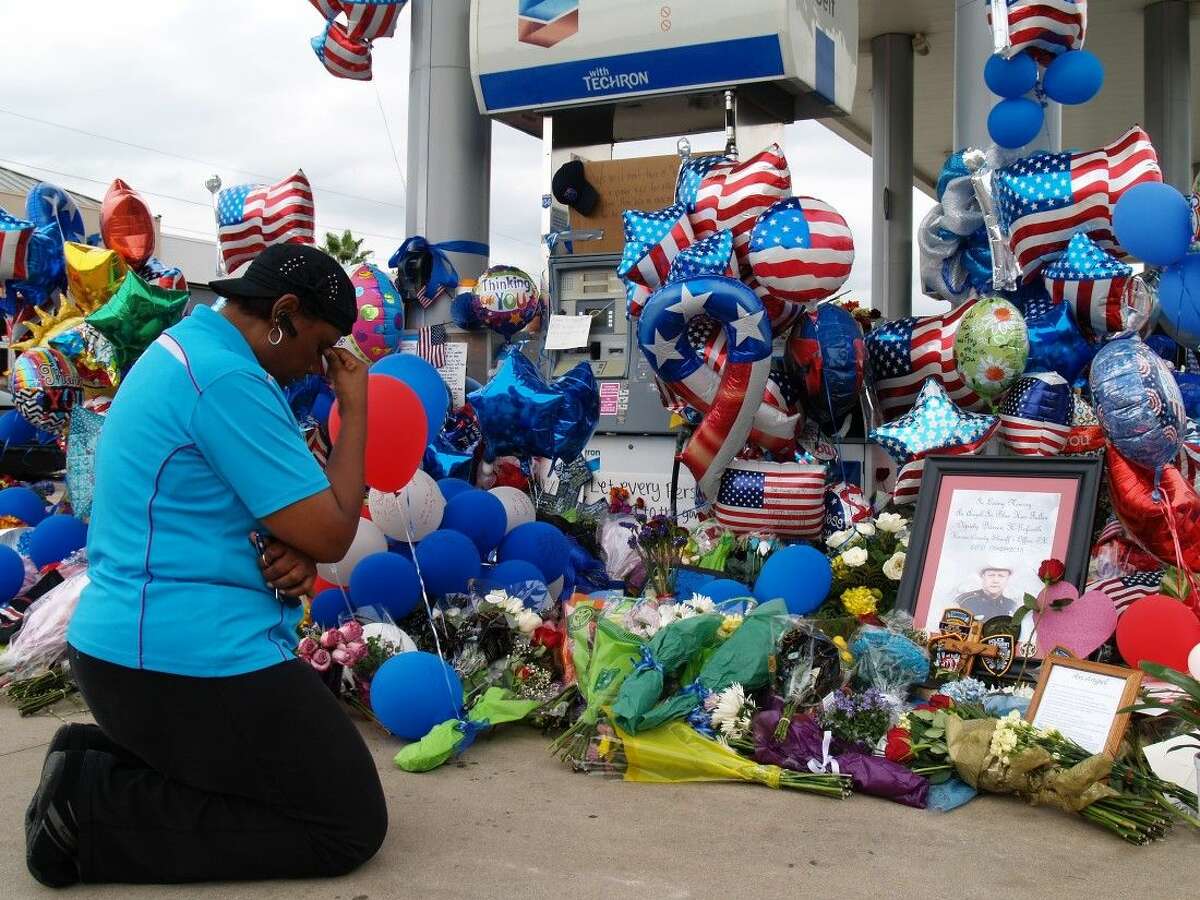 Yolanda Pounds, of Copperfield, knelt to pray next to the growing memorial at the site of the murder of Harris County Deputy Darren Goforth. Pounds attends Church of the Nazarene just around the corner from the gas station and was there to support the family and law enforcement community.