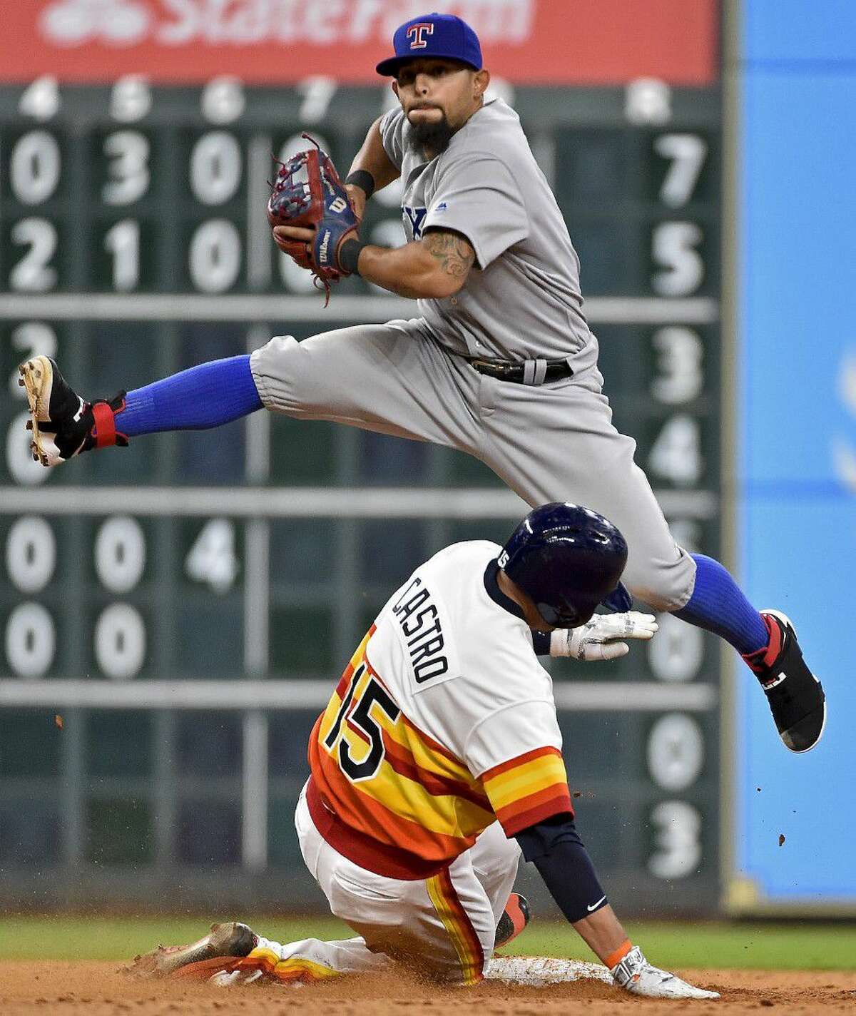 Texas Rangers second baseman Rougned Odor, top, leaps over the Houston Astros’ Jason Castro after a force-out in the ninth inning of a baseball game, Saturday.