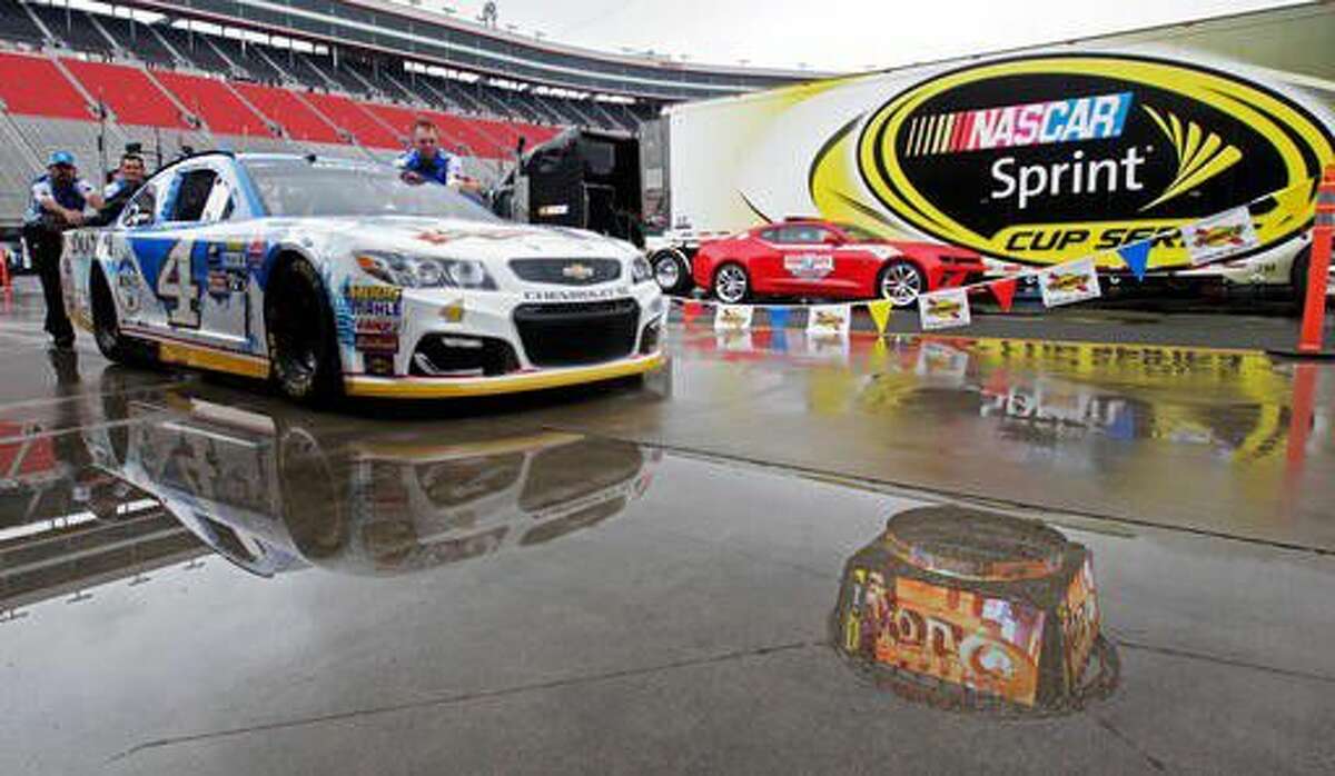 Crew members push the car of Kevin Harvick through a puddle as they prepare to practice for a NASCAR Sprint Cup Series auto race, Friday, Aug. 19, 2016 in Bristol, Tenn.