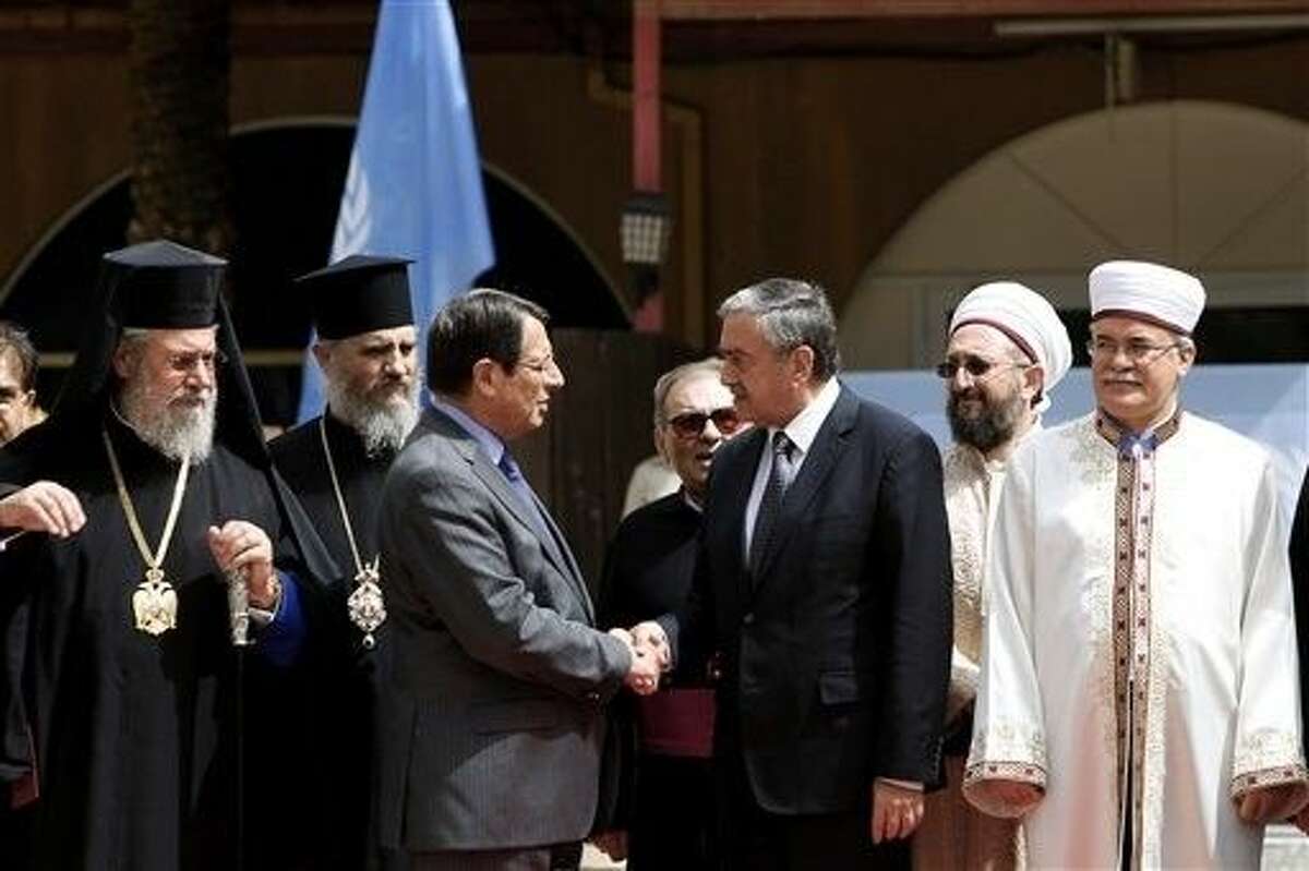 Cyprus’ president Nicos Anastasiades, Turkish Cypriot leader Mustafa Akinci shake hands as the Greek Cypriot Orthodox Archbishop Chrysostomos II, left, and the Turkish Cypriot religious leader Mufti Yalip Atalay look on after a meeting at UN buffer zone at Ledra palace hotel in divided capital Nicosia, Cyprus, Thursday, Sept. 10.