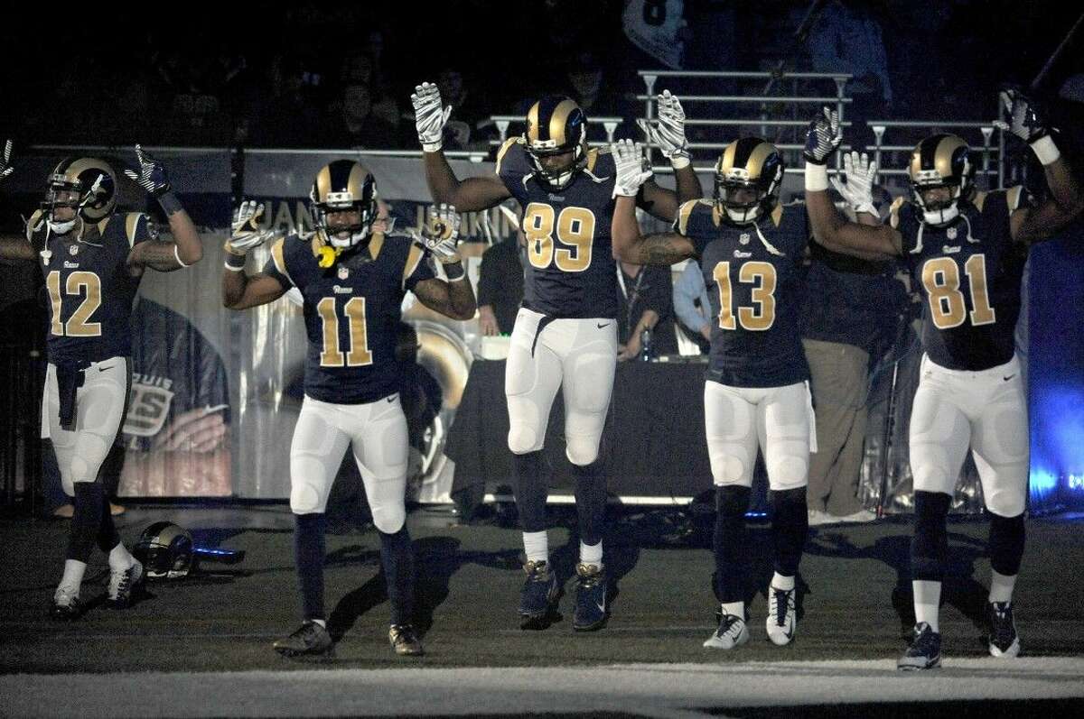 St. Louis Rams players Stedman Bailey (12), Tavon Austin (11), Jared Cook, (89) Chris Givens (13) and Kenny Britt (81) raise their arms in awareness of the events in Ferguson, Mo., as they walk onto the field during introductions before their game against the Oakland Raiders.