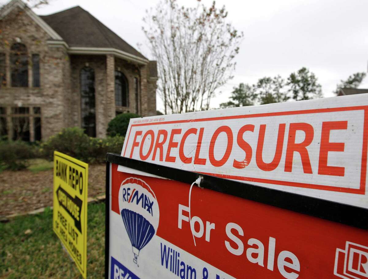FILE - A Jan. 10, 2009 file photo shows a bank repo and foreclosure for sale signs outside a foreclosed home in Houston. Foreclosure sales plunged 25 percent in the July-September quarter versus the April-June period and tumbled 31 percent from the third quarter last year, foreclosure listing firm RealtyTrac Inc. said Thursday, Dec. 2, 2010.