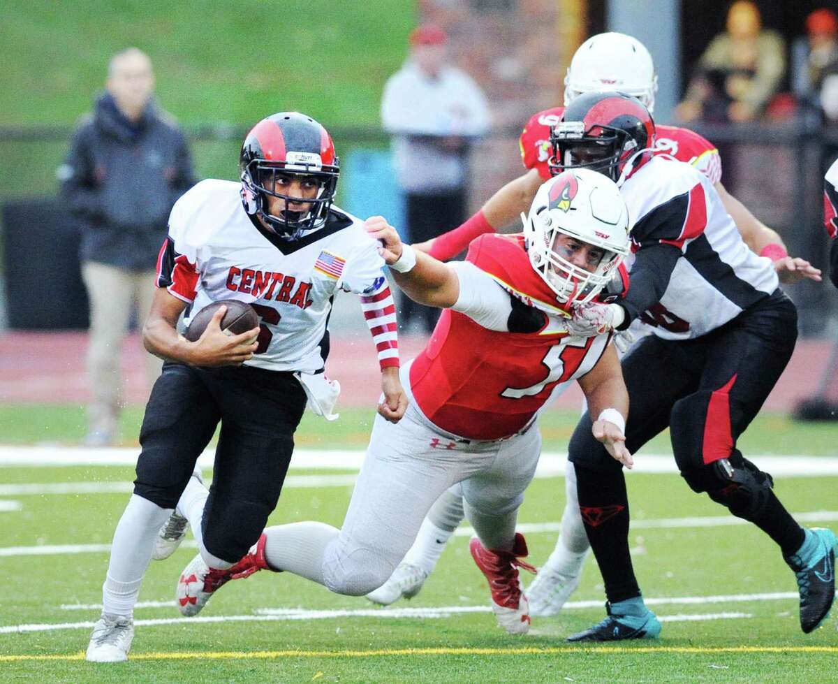 Bridgeport Central quarterback Mauricio Woods, left, on a keeper gets past the out-stretched arm of diving Greenwich defender Benjamin Kraninger (#51) during the high school football game between Greenwich High School and Bridgeport Central High School at Greenwich, Conn., Friday night, Sept. 30, 2016.
