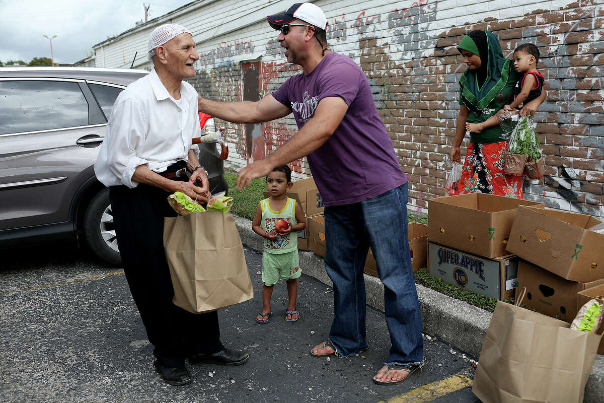 Abdul, who is originally from Iraq, hands out food and flowers donated by Trader Joe's to refugees at a northwest side apartment complex where refugees from many different countries have settled in recent years, on Saturday, Sept. 24, 2016.