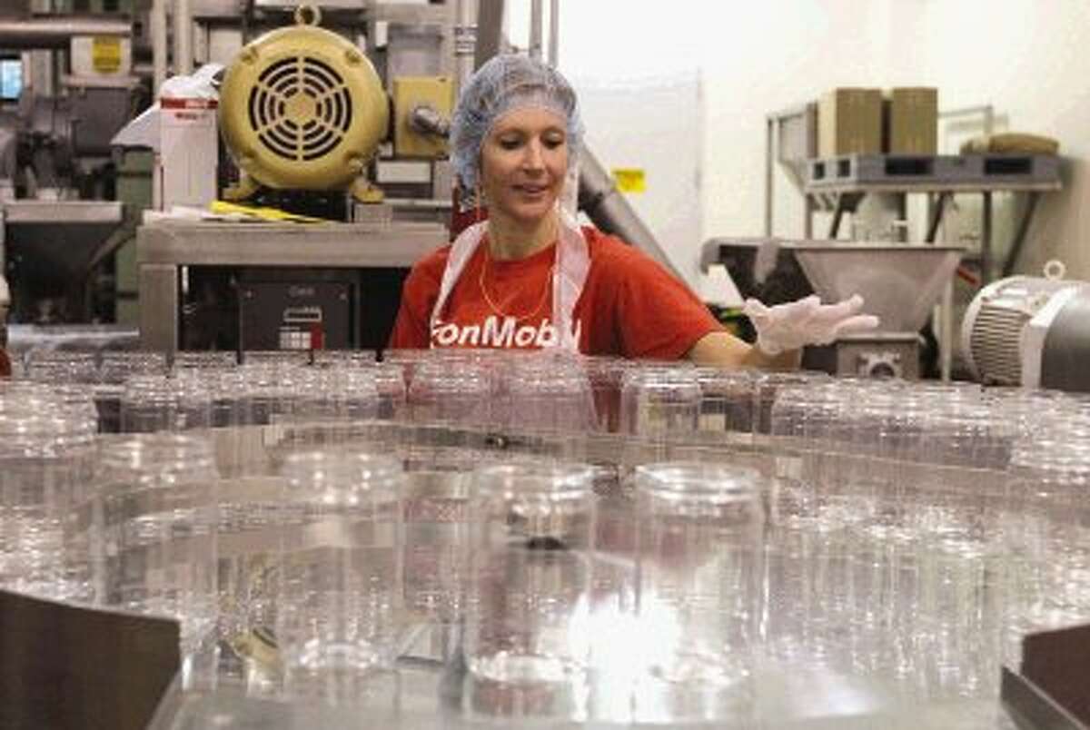 ExxonMobil volunteer Kristen Poteet inspects jars before they're automatically loaded with peanut butter at The Church of Jesus Christ of Latter-day Saints' peanut butter cannery in Spring. A team of 20 volunteers can produce 6,000 containers of peanut butter every four hours. Go to HCNPics.com to view more photos of how the peanut butter is made.