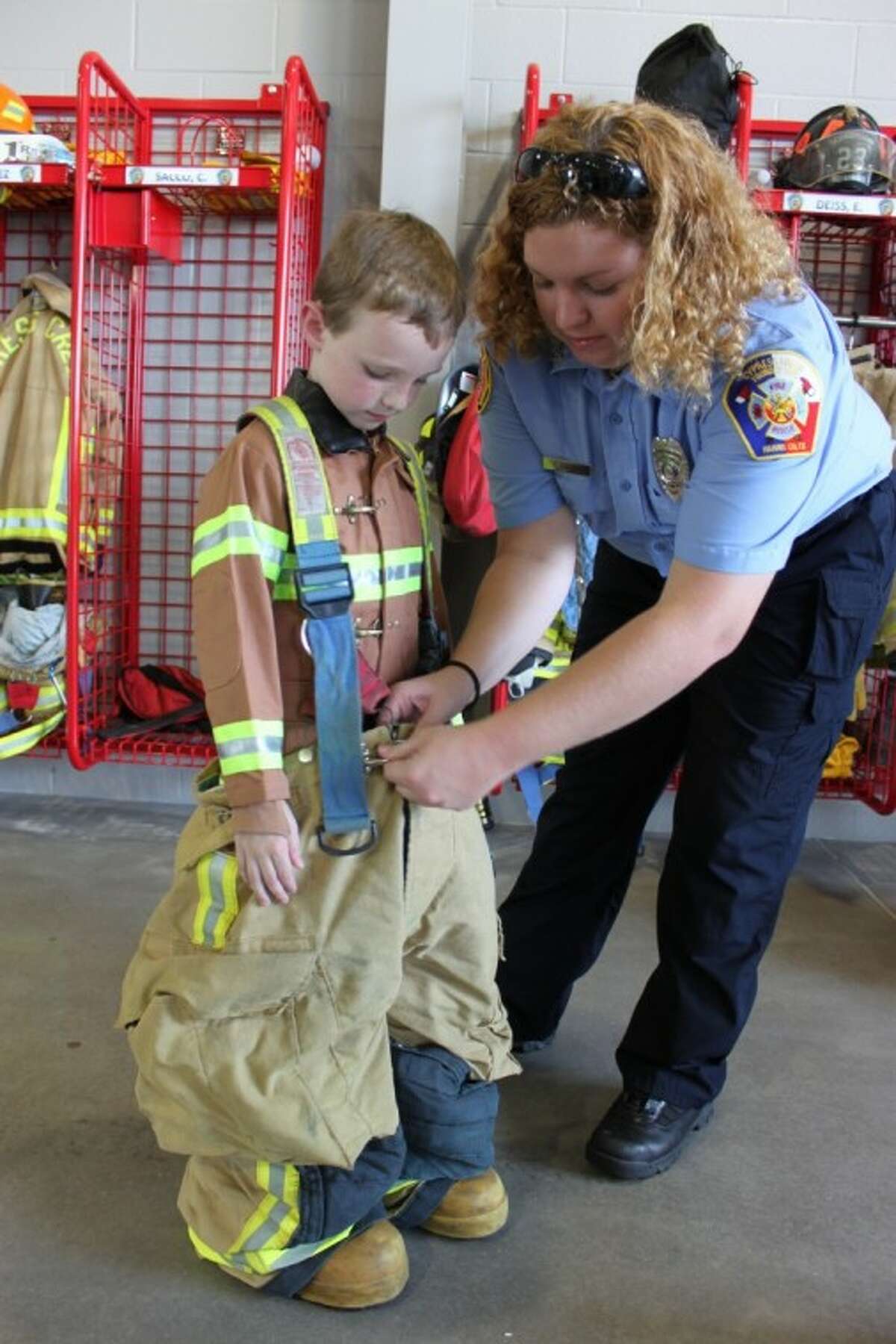 Volunteer firefighter Elizabeth Deiss helps aspiring firefighter Henry Jackson into some gear at the Cypress Creek Volunteer Fire Department's grand opening of Station 23 on Sept. 15.