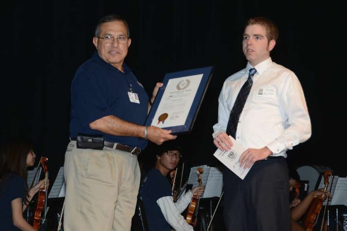 Cypress Ridge High School graduate Jason Baldwin presents Cypress Ridge principal Claudio Garcia with a proclamation from the State of Texas recognizing Dec. 11 as “Claudio Garcia Day” during an assembly at the school on Dec. 11.