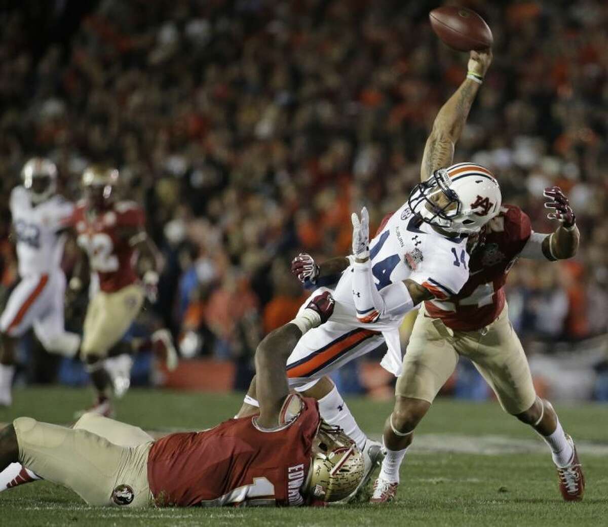 Auburn quarterback Nick Marshall (14) throws as he is hit by Florida State's Mario Edwards and Terrance Smith (24) during the first half of the NCAA BCS National Championship game. Florida State won 34-31.