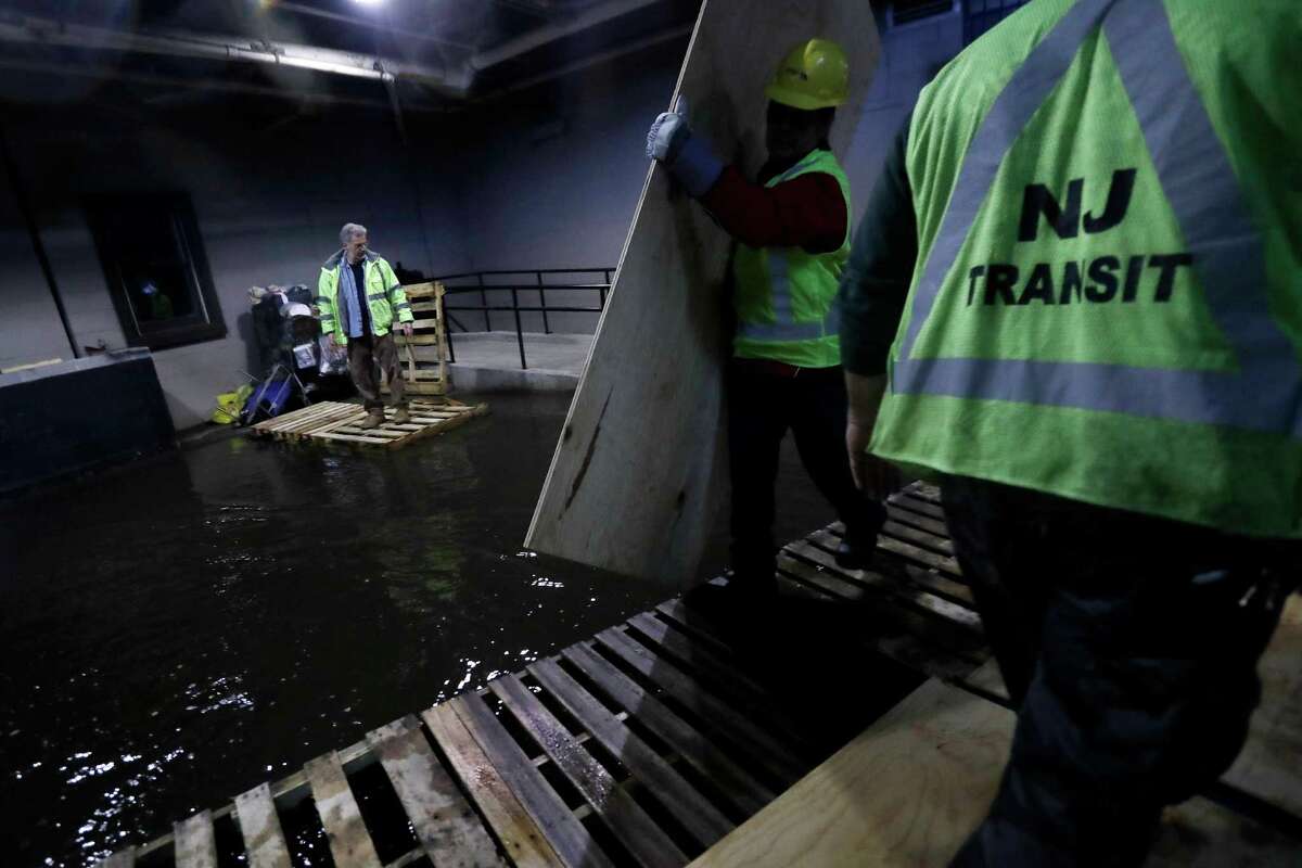 New Jersey Transit workers lay down pallets and boards for commuters to walk on a flooded hallway adjacent to the site of a train crash at the Hoboken Terminal, Friday, Sept. 30, 2016, in Hoboken, N.J. Commuters are using alternative travel in and out of Hoboken a day after a commuter train crashed into the rail station, killing one person and injuring more than 100 people. (AP Photo/Julio Cortez) ORG XMIT: NJJC104