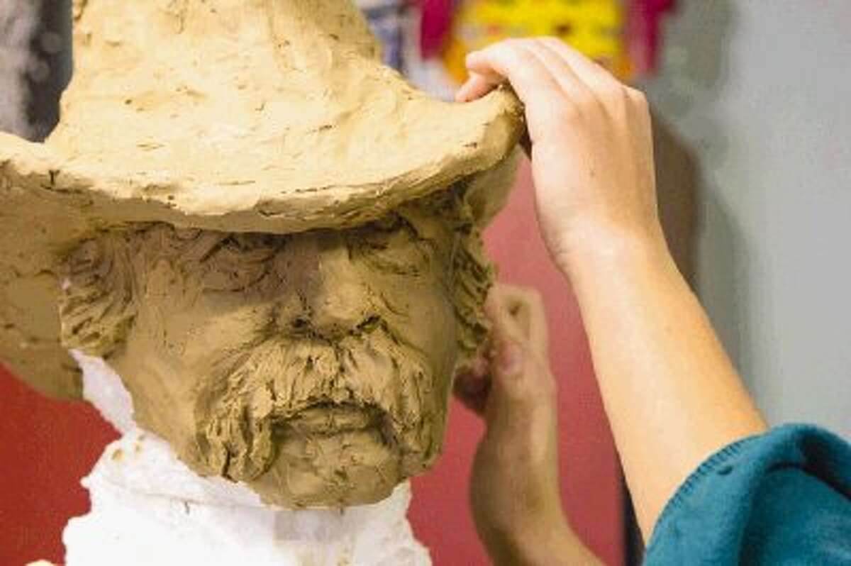 Clay is added to the Styrofoam figure of a rancher Friday in Conroe.  The rancher will be part of a monument, Pioneers of Montgomery, that will eventually be placed at Cedar Brake Park in Montgomery. Charles Bellinger Stewart, the centerpiece of the monument, will be dedicated Saturday at the park.