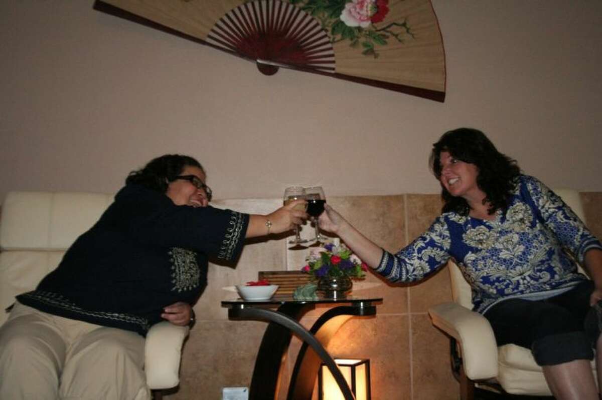 Connie Segora (left) and Gwendolyn Condoleo try out the reflexology foot massage room over glasses of wine.