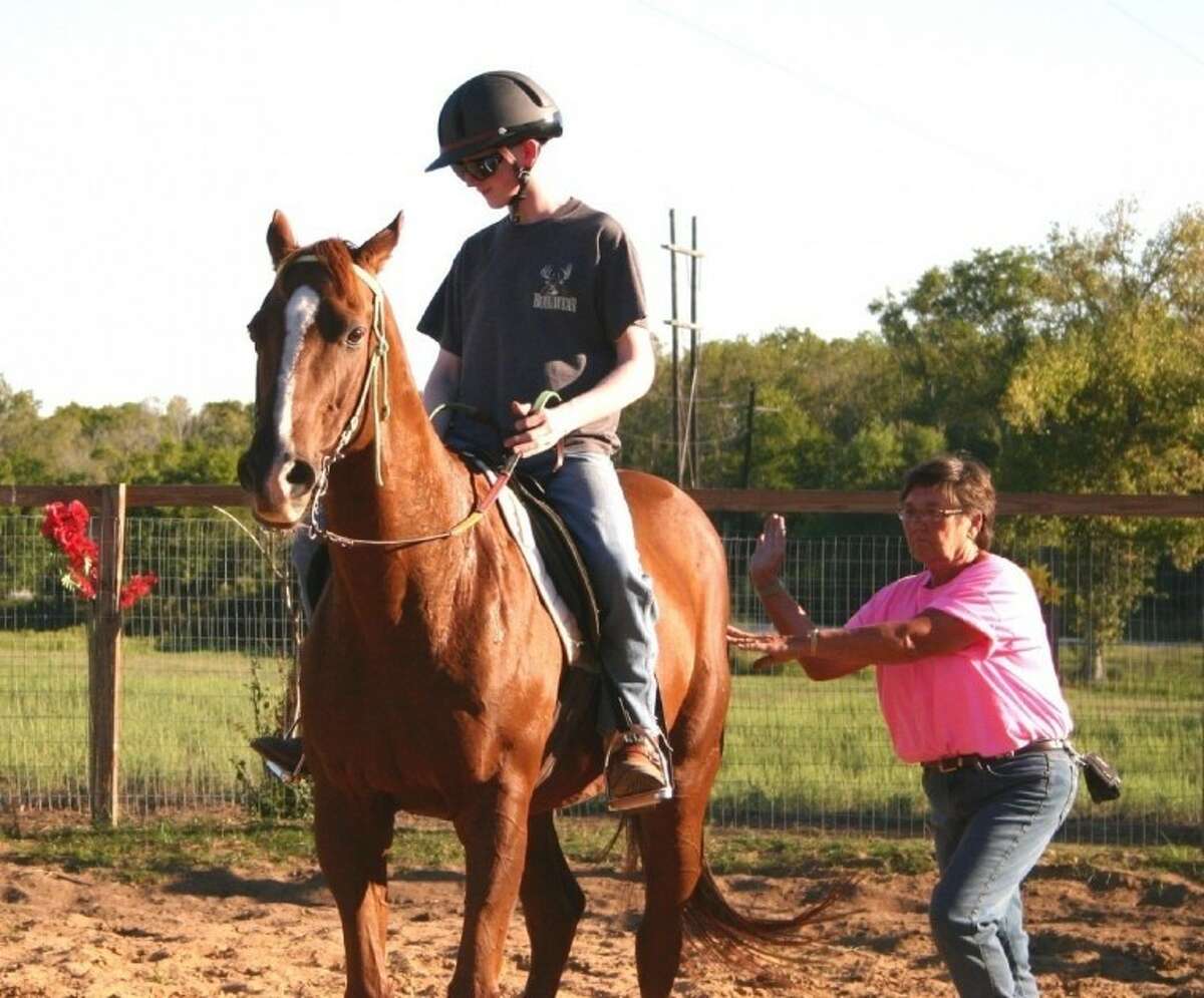 Donna Wiebelhaus, executive director of the SpiritHorse Therapeutic Riding Center of Liberty, gives Kyle's horse, Vern, a giddyup during a riding lesson.