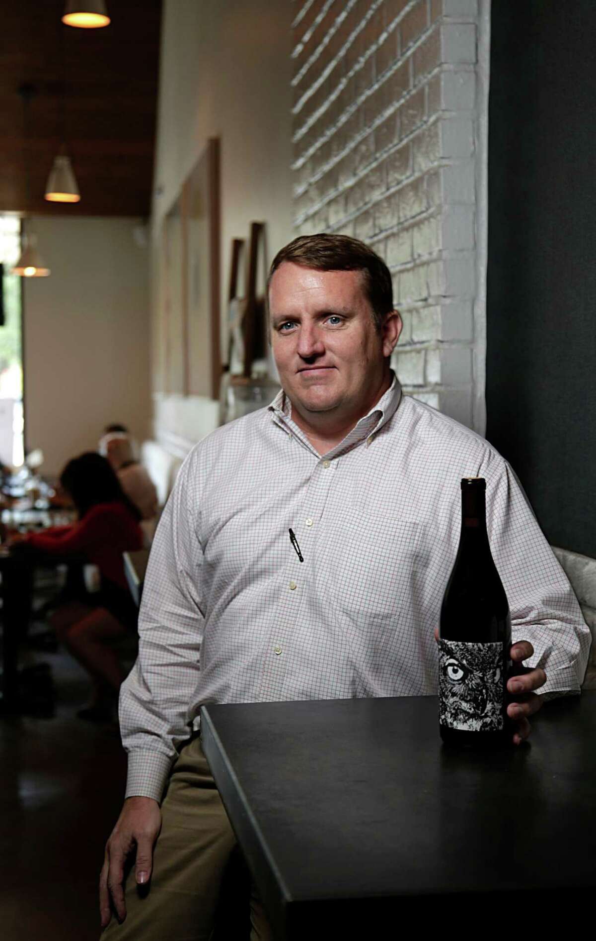 Brendon Fetzer poses for a portrait with a bottle of PARA MARIA de los tecolotes 2014 Red Wine Santa Barbara County at Wood Bar Aug. 4, 2016, in Houston. ( James Nielsen / Houston Chronicle )