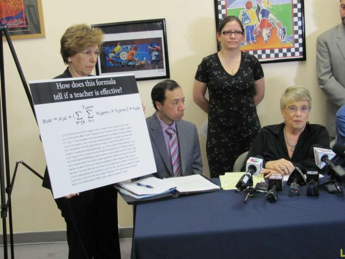 American Federation of Teachers President Randi Weingarten, left, displays the controversial math formula used by Houston ISD that is the subject of a federal lawsuit filed by seven teachers, including Daniel Santos, seated at left, and Myla Van Duyn, standing at right, along with the Houston Federation of Teachers, represented by President Gayle Fallon, seated right.