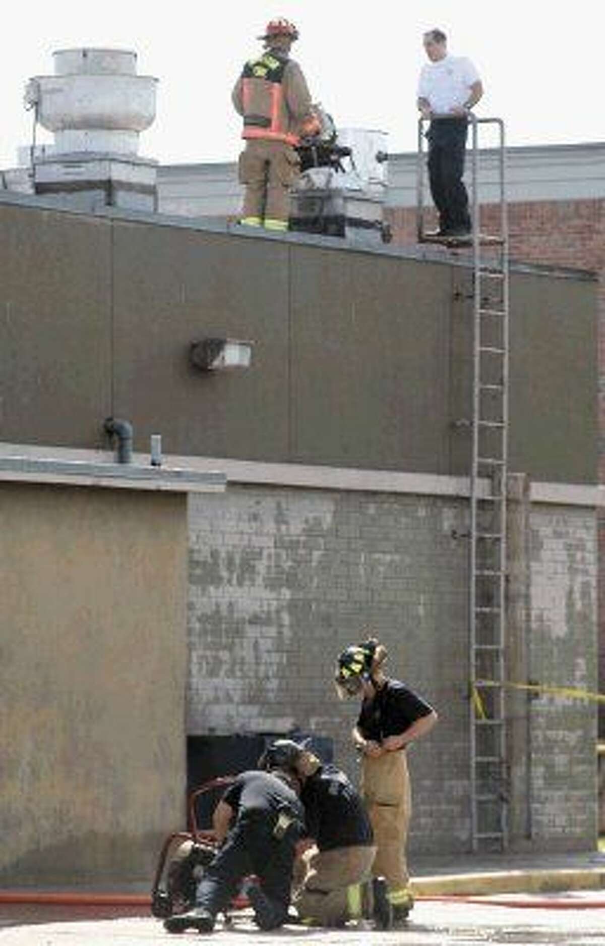 Houston Firefighters set up a fan to remove smoke as others work on the roof of the 888 Bistro Chinese restaurant after an early morning fire Monday.