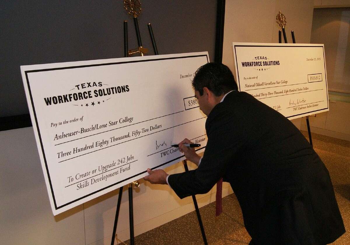 TWC Chairman Andres Alcantar signs checks for the $913,865 Skills Development Fund grants given to Lone Star College by Texas Workforce Solutions to help train current and new employees at National Oilwell Varco and Anheuser-Busch.