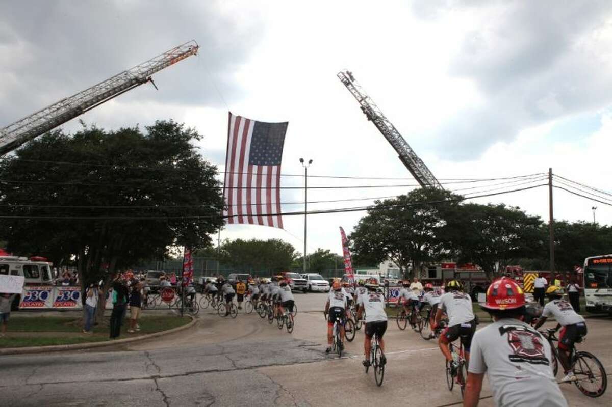 The Brotherhood Ride goes under a American flag held by ladders from HFD stations 51 and 68 off Gessner into HFD Station 68.
