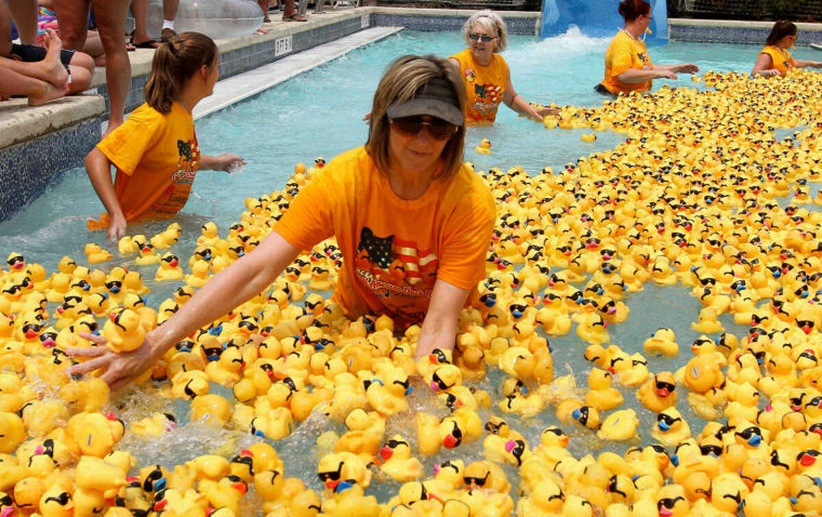 A volunteer pushes rubber ducks during the Montgomery County Emergency Assistance Agency's annual Duck Race in 2013 where 5,000-10,000 ducks float around the pool at the Rob Fleming Aquatic Center in Creekside Park.