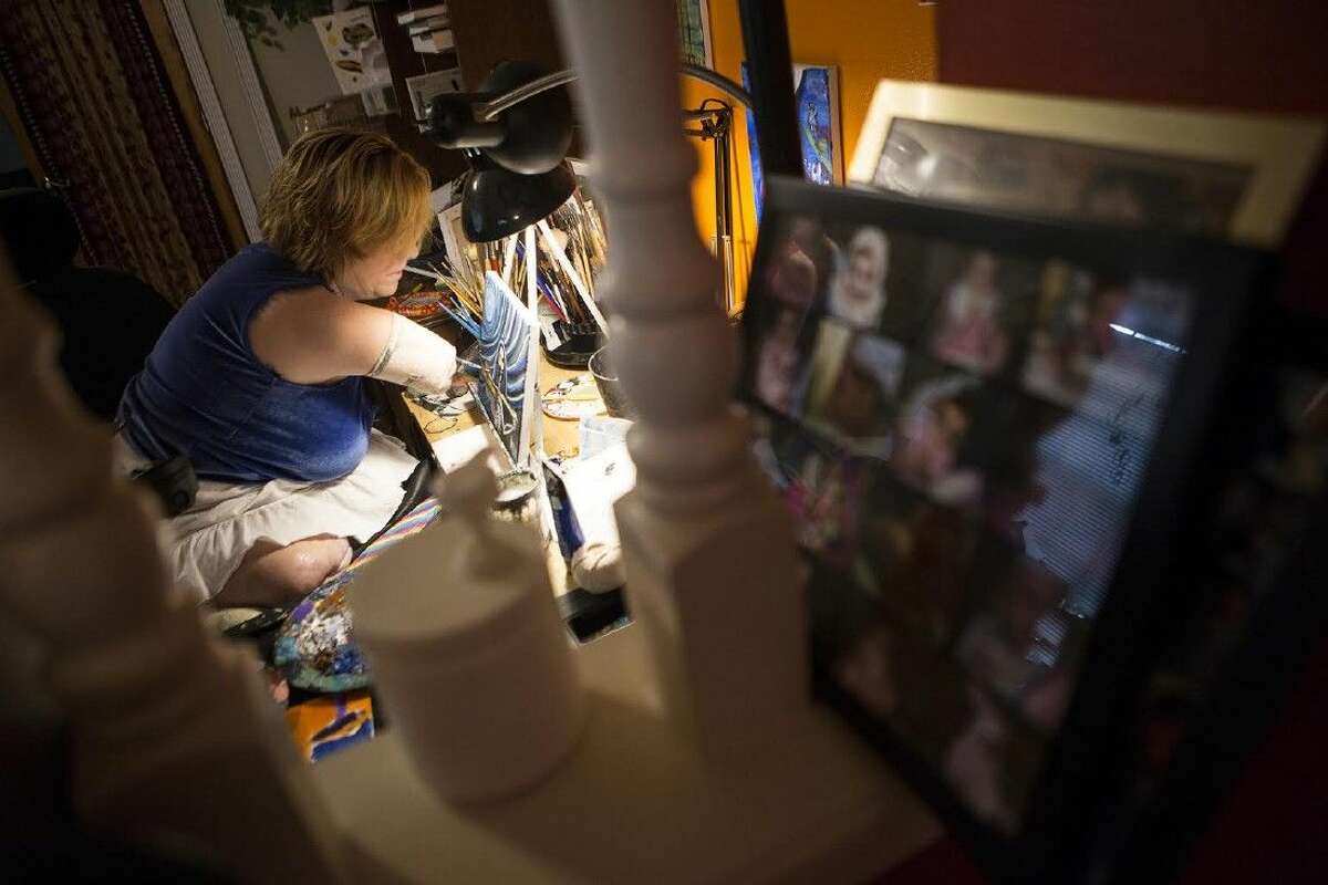 Katy Hayes paints at her home June 20, 2015, in Kingwood. Hayes lost her limbs to an infection after the home birth of her third child and has persevered to continue painting for herself while leading classes for members of the community on Sundays.