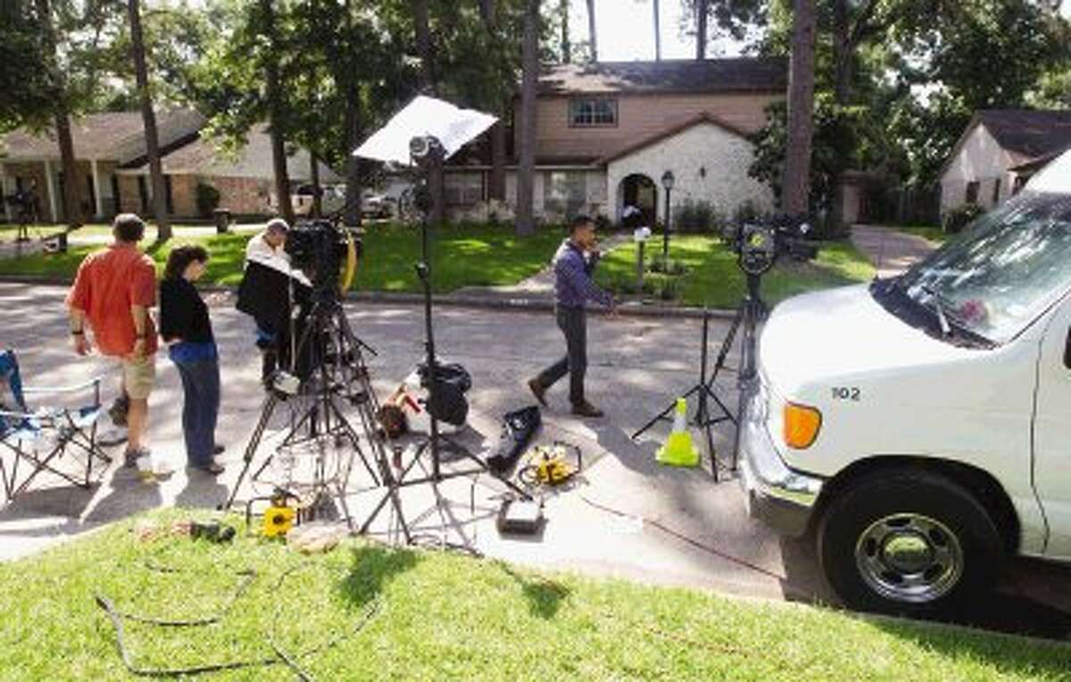 Media waits outside a home where six people were shot shot Thursday in Spring. Four children and two adults were killed Wednesday after an apparent domestic dispute.