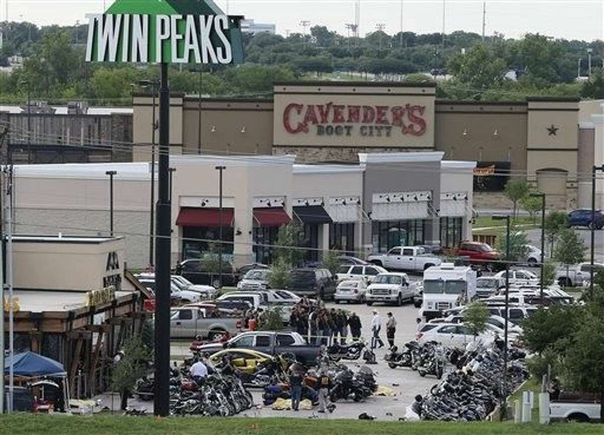 FILE - In this May 2015 file photo, authorities investigate a shooting in the parking lot of Twin Peaks restaurant in Waco, Texas. The family of a biker slain in a shootout outside the Waco restaurant has sued the restaurant's parent company alleging negligence, according to a lawsuit filed Wednesday in Dallas County.