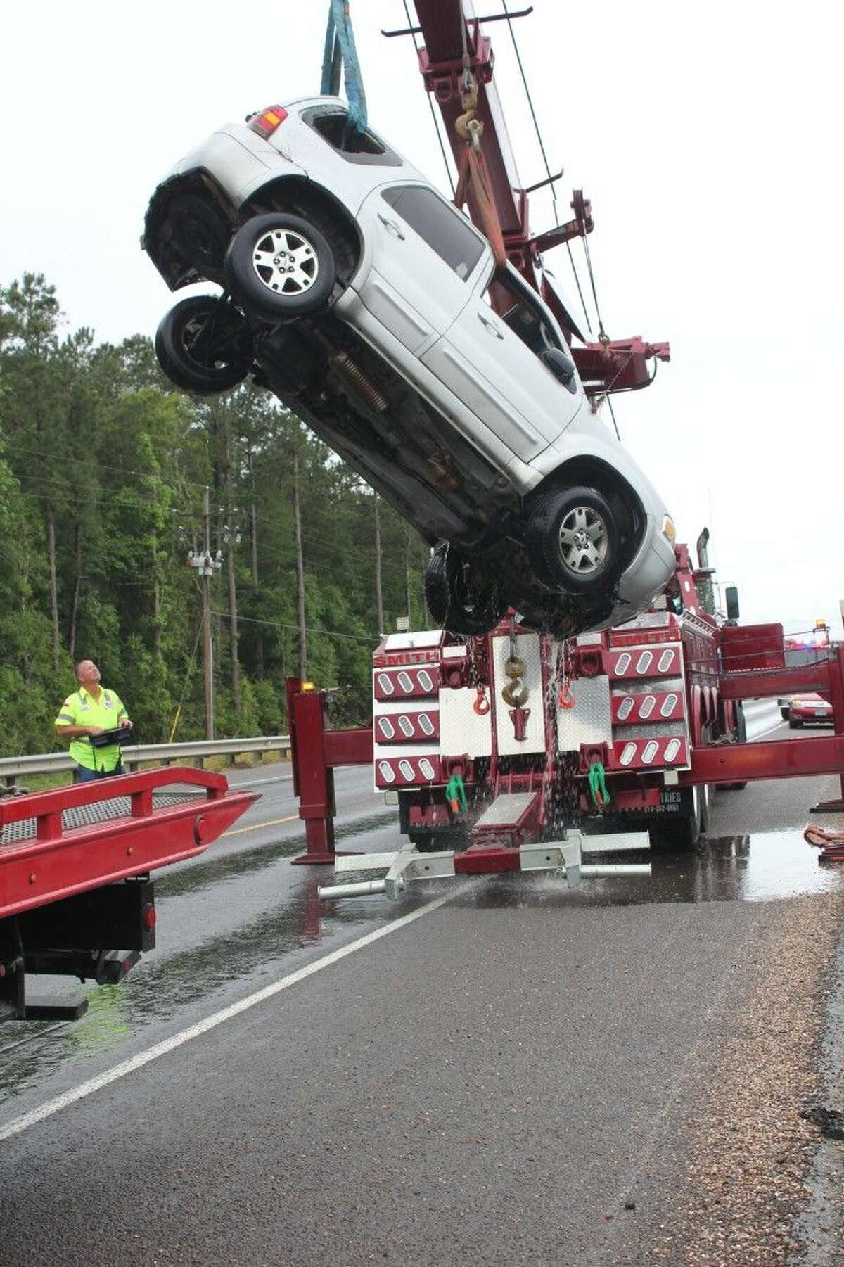 Water pours out of a Ford Escape while being lifted into the air by a Smith Towing truck operated by Jesse Burch. The Ford Escape was destroyed by floodwaters on Monday, April 18, at the Tarkington Bayou bridge on SH 321.