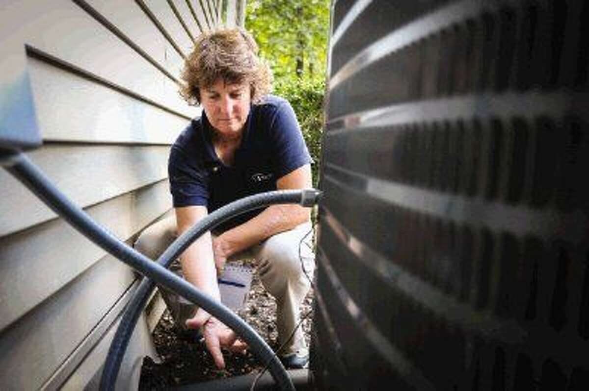 Photo by Michael Minasi Sybil Bradley, a certified home inspector through Pillar To Post Home Inspectors, demonstrates some of the items she would look for while inspecting an air conditioning unit at her home in Conroe.