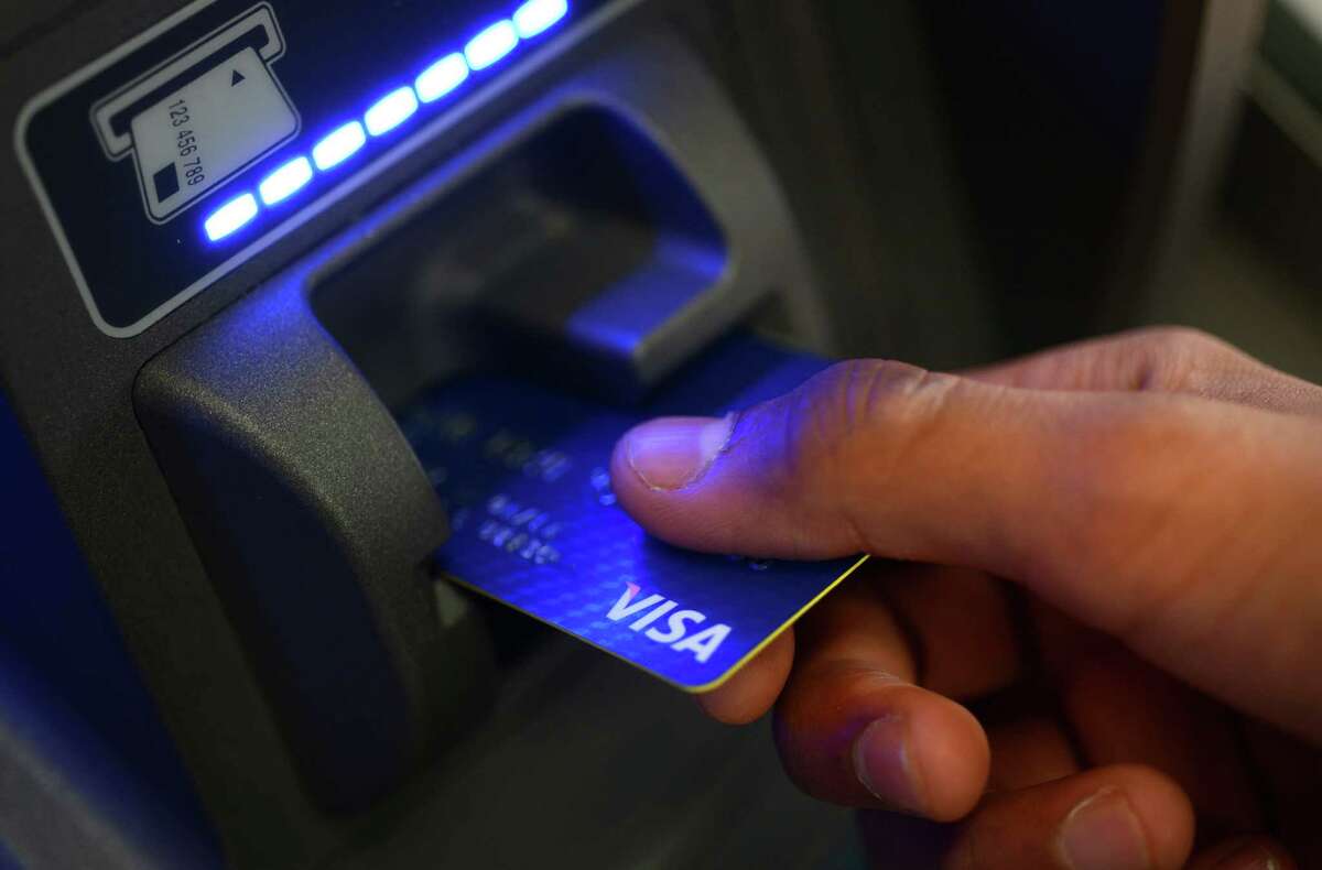 A photo illustration shows a customer scanning a credit card into a gas station ATM in Derby.