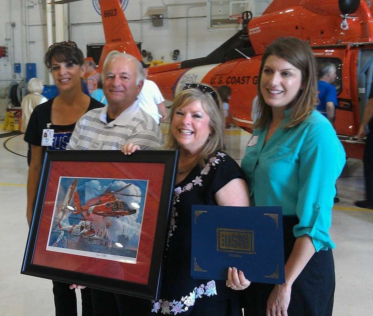 U.S. Coast Guard Air Station Houston Executive Officer, Commander Christopher Hulser, spoke to the volunteers about what their service means to troops and military family members before presenting a lithograph to USO Houston Volunteers of the Year, Richard and Nancy Foisner.