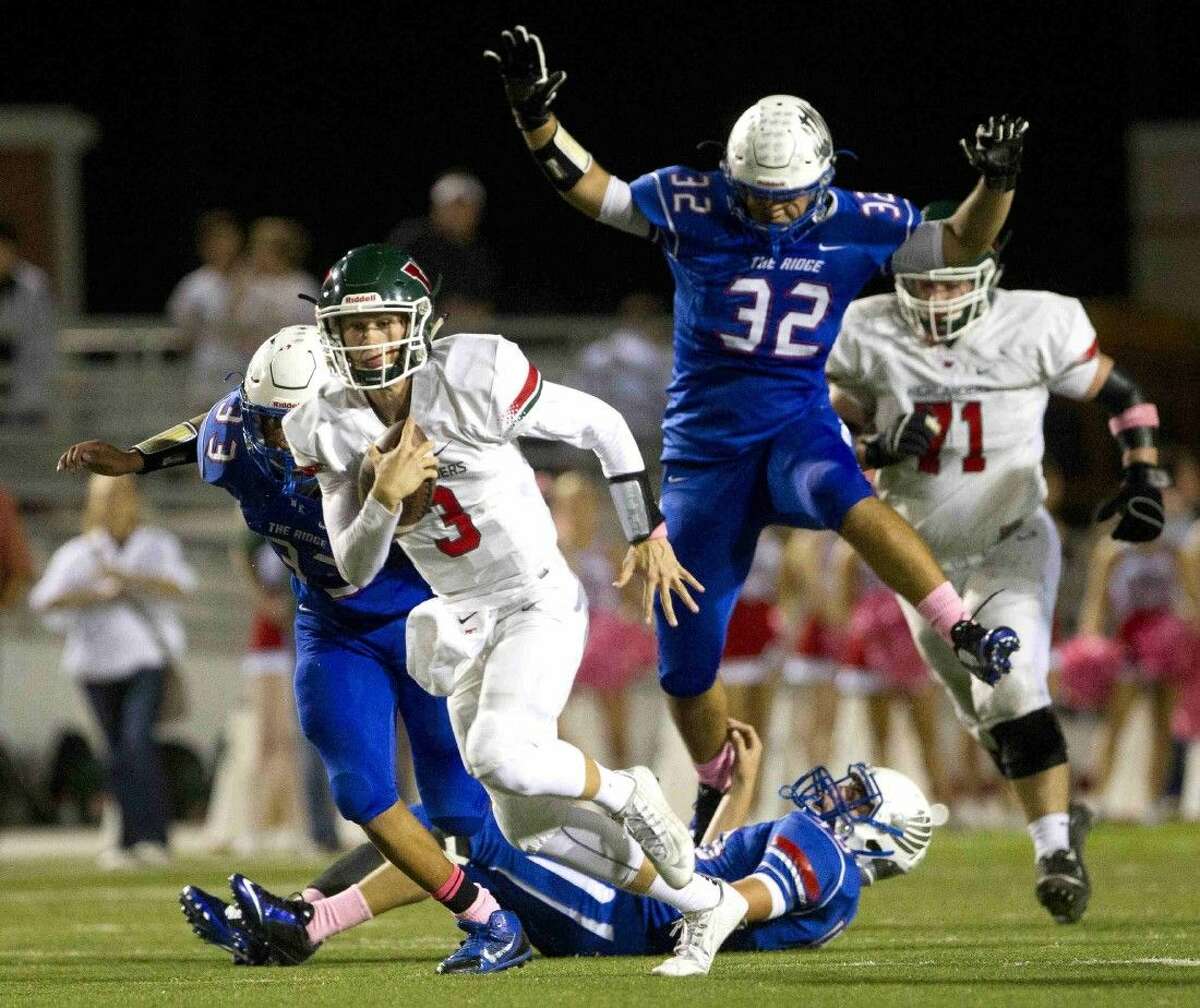 The Woodlands quarterback Eric Schmid runs for a first down and more as Oak Ridge defensive end Lane Tuck leaps over linebacker Brennan Young during the first half of football game Friday. To view or purchase this photo and others like it, visit HCNpics.com.