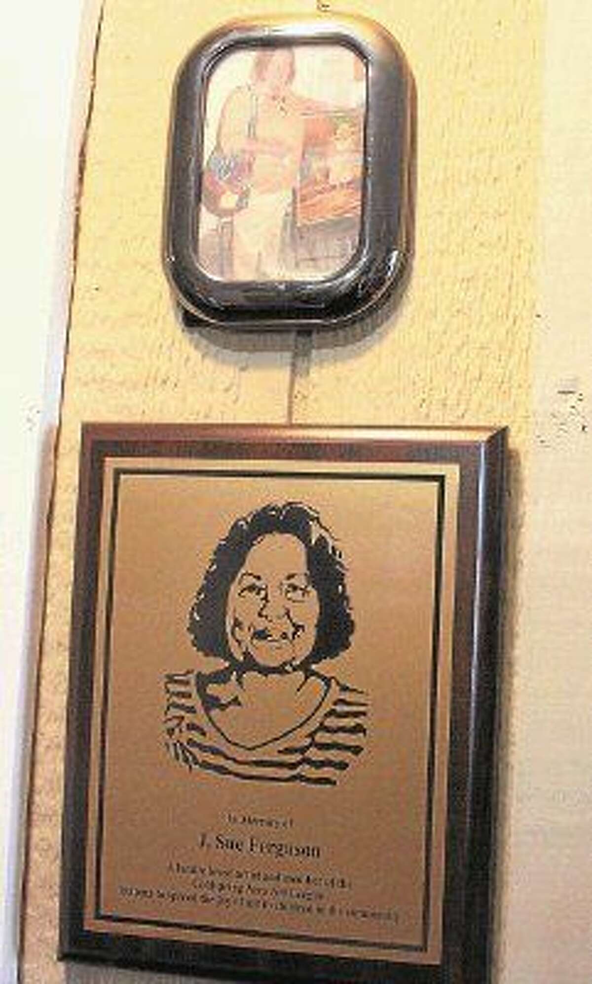 A photo and a plaque of Sue Ferguson rest on a post in Chelten’s Photo Gallery.