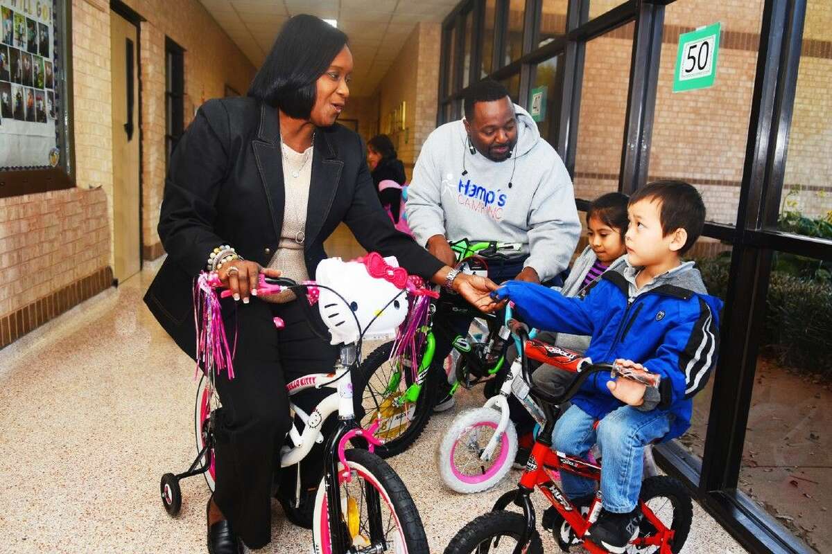 Bang Elementary School principal Erwann Wilson and former football star Rodney Hampton enjoy riding the new bicycles with two students Angelik Palomo and Adam Tran, who were rewarded bikes.
