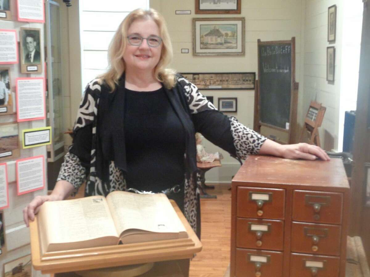 Paula Fielder, library coordinator for Dayton ISD, stands with an old oversized abridged dictionary that was used at Woodrow Wilson Junior High after 1962 and a small card catalog that was used at Colbert School prior to the computer automation of libraries. Both items were donated to the Old School Museum in Dayton.