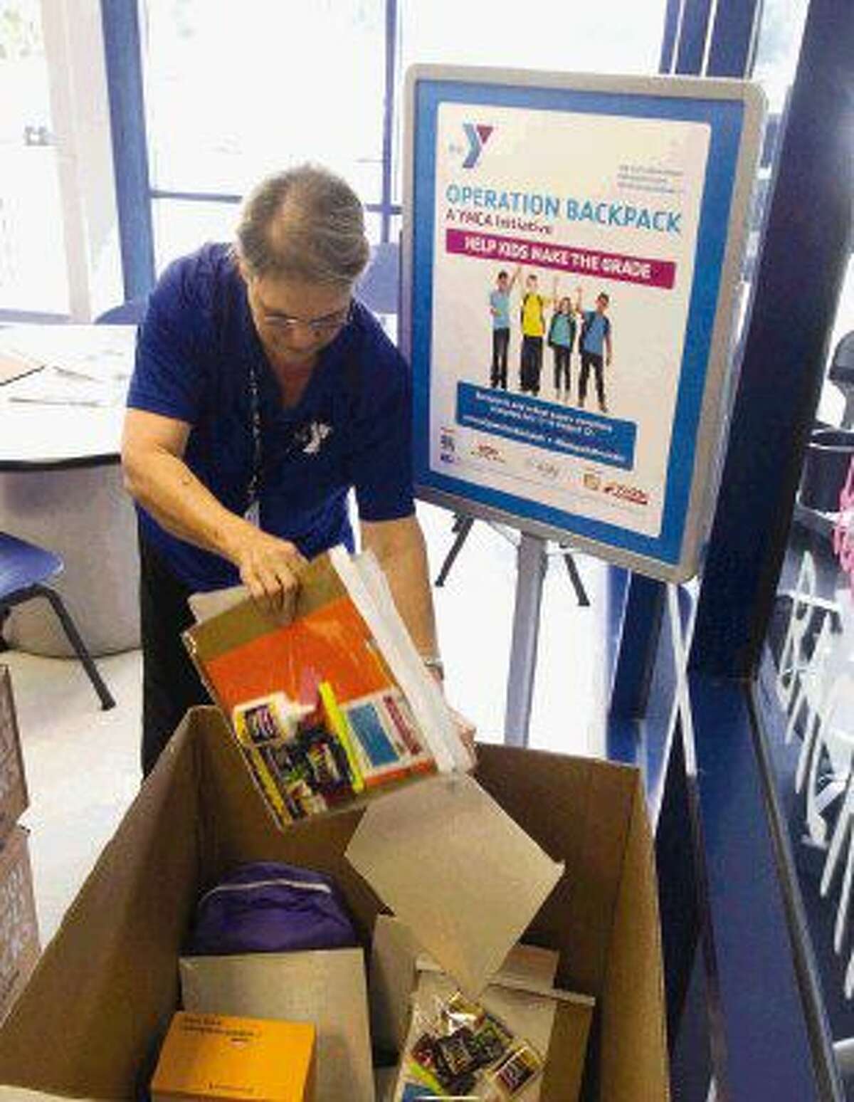 Terri Walters loads school supplies into a bin in support of Operation Backpack at the Conroe Family YMCA Tuesday in Conroe.
