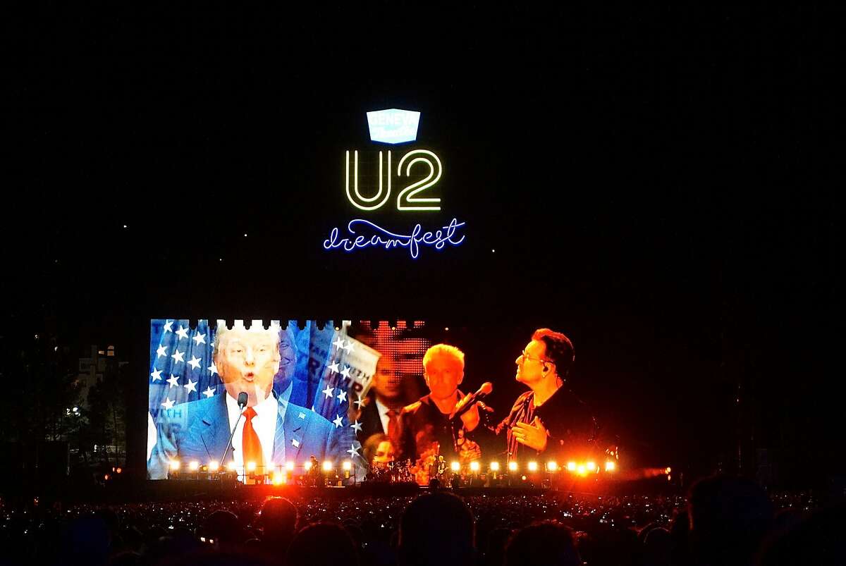 U2 lead singer Bono conducts a mock debate with a video image of Republican Presidential candidate Donald Trump on the main stage during the Concert for the Kids at the Cow Palace. Oct. 2016.