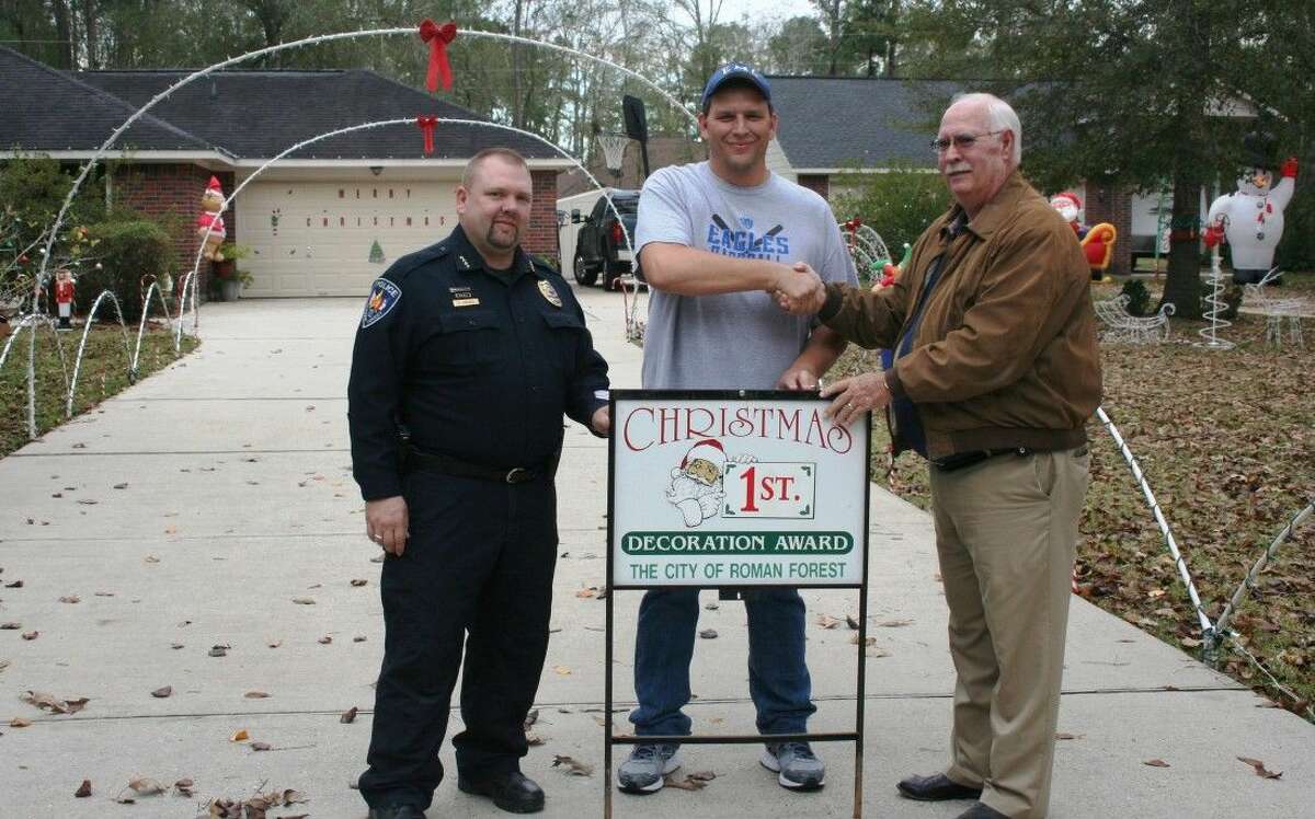 Roman Forest Police Department Chief Stephen Carlisle and Mayor Ray Ricks present resident Mark Shaw with the first place award for the local Christmas lights competition.