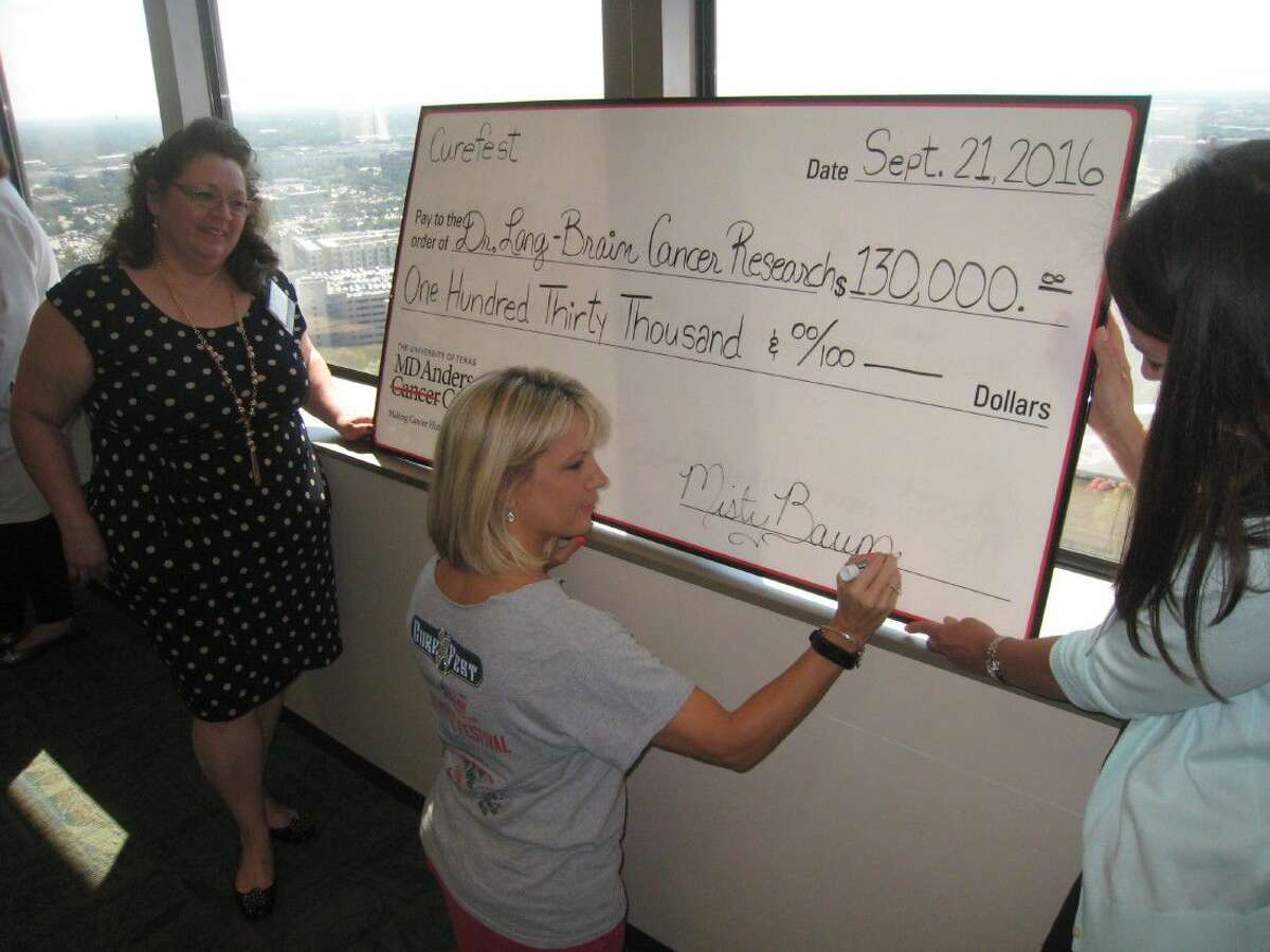 Misty Baumann signs the check Sept. 21 before the presentation of $130,000 to Dr. Frederick Lang for continued brain cancer research at University of Texas M.D. Anderson Cancer Center.