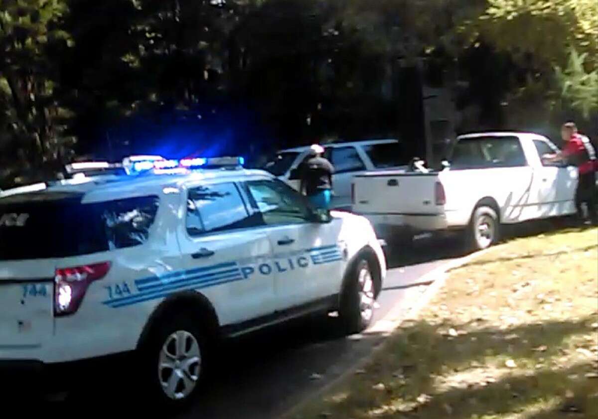 In this image taken from video recorded by Rakeyia Scott on Tuesday, her husband, Keith Lamont Scott, center, stands amid Charlotte police cars and other vehicles moments before he is shot by a police officer in Charlotte, N.C.