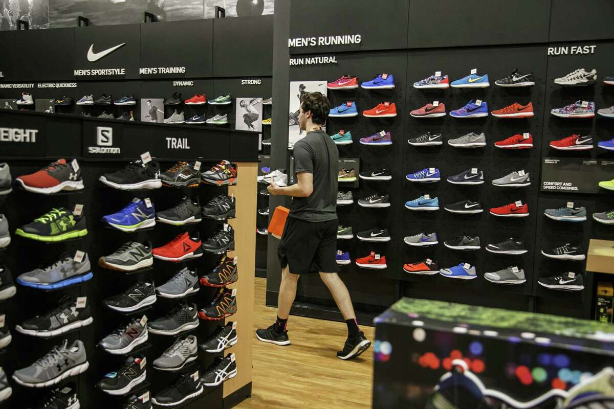 An employee carries Nike Inc. sneakers for a customer at a Dick's Sporting Goods Inc. store in Sterling Heights, Michigan. The company is preparing to open a store in Friendswood near Baybrook Mall.