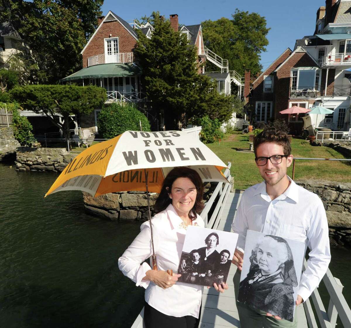 Holding a period umbrella calling for women’s right to vote, Coline Jenkins, the great-great-granddaughter of suffragist Elizabeth Cady Stanton, and her son, Eric Jenkins-Sahlin, display photos of their famous ancestor at their home, at left, in Greenwich.