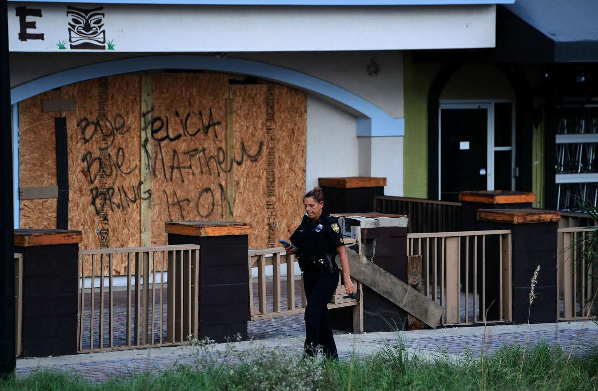 A police officer walks past a closed store in Jacksonville Beach, Florida, on October 8, 2016, after Hurricane Matthew passed the area. A weakened Hurricane Matthew churned just off the coast of the US states of Georgia and South Carolina Saturday, threatening deadly floods after leaving more than a million people without power in Florida and claiming five lives. The full scale of the devastation in hurricane-hit rural Haiti became clear as the death toll surged past 400, three days after Hurricane Matthew leveled huge swaths of the country's south. / AFP / Jewel SAMAD (Photo credit should read JEWEL SAMAD/AFP/Getty Images)