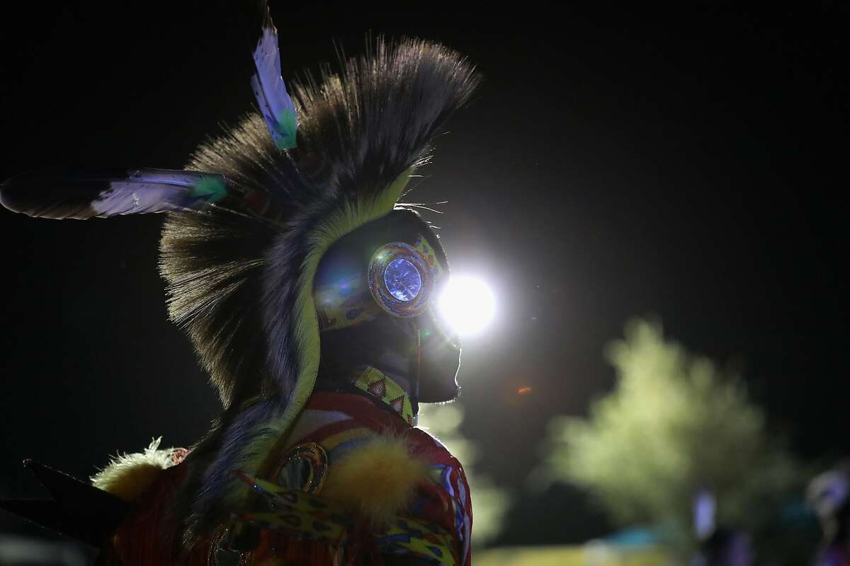 YSLETA DEL SUR PUEBLO, TX - OCTOBER 01: A Native American dancer watches as fellow traditional dancers perform at the "Rocking the Rez" Pow Wow on October 1, 2016 in Ysleta del Sur Pueblo, Texas. The pow wow, held on the reservation near the U.S.-Mexico border in west Texas, drew in First Nation peoples from around the United States. Tribal leaders expressed support for protesters that have blocked construction of the Dakota Access Pipeline. (Photo by John Moore/Getty Images)