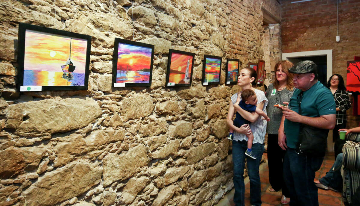 Art enthusiasts admire some of the paintings on display during the Shira De Llano Art in Health exhibit, hosted by the Border Region Behavioral Health Center, Wednesday evening at Gallery 201.