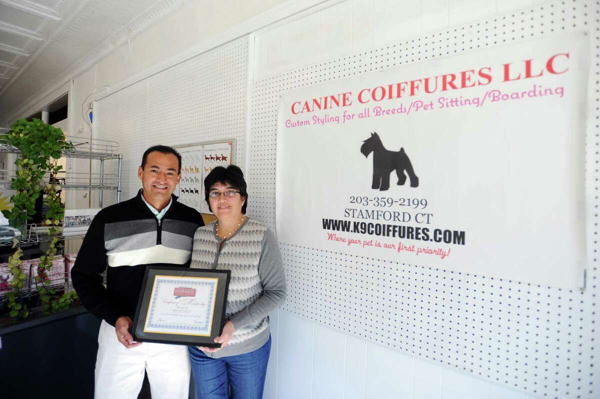 David Yika, second vice president of the Greater Stamford Hispanic Chamber of Commerce, and his wife Mercedes Nacarino hold their Greater Stamford Hispanic Chamber of Commerce membership inside their Canine Coiffures store on Hope Street in Stamford, Conn. on Tuesday, Oct. 11, 2016.